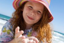 Porträt eines kleinen Mädchens, das in die Kamera lächelt, Sand in den Händen, im Freien — Stockfoto