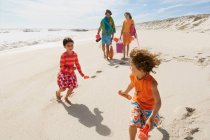Родители и двое детей прогуливаются по пляжу, на открытом воздухе — стоковое фото