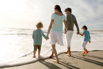 Pais e duas crianças andando na praia, vista traseira, ao ar livre — Fotografia de Stock