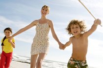 Mother and two children walking on the beach, outdoors — Stock Photo