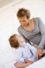 Senior woman with little girl on bed — Stock Photo