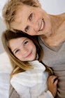 Senior woman and little girl smiling for the camera, indoors — Stock Photo