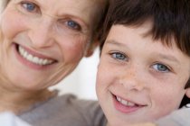 Senior woman and little boy smiling for the camera, indoors — Stock Photo