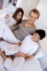 Mulher sênior e duas crianças segurando presentes, dentro de casa — Fotografia de Stock