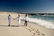 Couple and senior woman holding hands on beach — Stock Photo