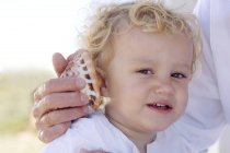 Portrait of little boy with shell against ear — Stock Photo
