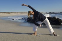 Giovane donna bionda che si estende sabbiosa sulla spiaggia — Foto stock