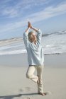 Donna matura che fa yoga sulla spiaggia di sabbia — Foto stock