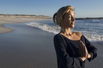 Mujer joven y relajada en actitud de yoga en la playa - foto de stock