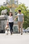 Couple running with puppy on street in city — Stock Photo