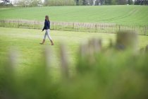 Teenage girl walking on green field — Stock Photo