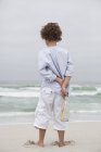 Мальчик держит бутылку с сообщением на песчаном пляже — стоковое фото