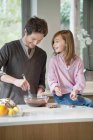 Чоловік перемішує суміш в мисці з дочкою на кухні — стокове фото