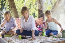 Children eating food in tree house in summer garden — Stock Photo