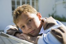 Portrait of pensive boy resting on deck chair outdoors — Stock Photo