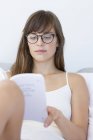 Close-up of young woman in eyeglasses reading book — Stock Photo