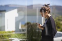 Mujer joven reflexiva usando el teléfono inteligente mientras está al aire libre - foto de stock