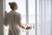Розслабленої молодої жінки стоять біля вікна будинку — стокове фото