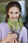 Portrait of young woman smelling a rosemary plant — Stock Photo