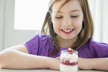 Улыбающаяся маленькая девочка смотрит на стакан мороженого — стоковое фото