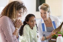 Seniorin mit Tochter und Enkelin redet in Küche — Stockfoto