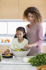 Glückliche junge Frau mit Tochter bereitet sich in Küche vor — Stockfoto