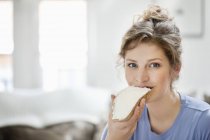 Porträt einer lächelnden Frau, die Toast mit Sahneaufstrich isst — Stockfoto