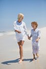 Mujer caminando en la playa con su hijo - foto de stock