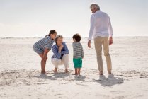 Счастливые бабушка и дедушка с внуками наслаждаются на пляже — стоковое фото