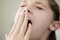 Close-up de adolescente bocejando com a mão no rosto — Fotografia de Stock
