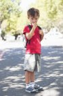 Портрет милого мальчика, стоящего с пальцем во рту на улице — стоковое фото
