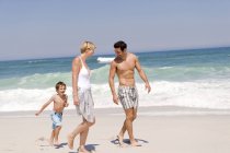 Happy family walking on sandy beach — Stock Photo