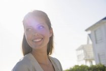 Крупный план элегантной женщины, улыбающейся в солнечном свете на открытом воздухе — стоковое фото