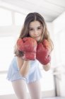 Портрет девушки в боксёрских перчатках, стоящей в комнате — стоковое фото