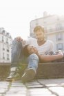 Mujer acostada en el regazo de un hombre en la cornisa de un canal, París, Isla de Francia, Francia - foto de stock