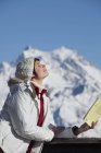 Jovem com livro desfrutando de sol de inverno com montanhas no fundo — Fotografia de Stock
