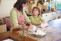 Nonna e bambino impastando la pasta a cucina — Foto stock