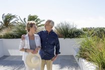 Счастливая старшая пара смотрит друг на друга, стоя на террасе в саду — стоковое фото