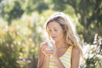 Женщина с чашкой кофе в летнем саду — стоковое фото