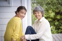 Portrait of happy mother sitting with adult daughter on porch — Stock Photo