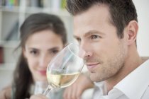 Чоловік п'є біле вино з дружиною на фоні — стокове фото