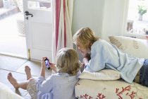Enfants utilisant un téléphone portable à la maison — Photo de stock