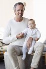 Ritratto di padre felice con figlioletta carina seduta in salotto — Foto stock
