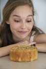 Крупный план взволнованной девочки-подростка, смотрящей на торт — стоковое фото