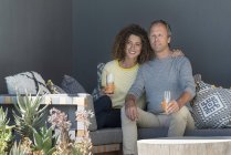 Счастливая пара сидит на диване и пьет овощной сок — стоковое фото