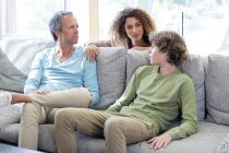 Família feliz falando no sofá na sala de estar em casa — Fotografia de Stock