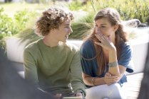 Happy brother and sister sitting in garden and talking — Stock Photo