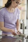 Thoughtful woman washing dishes in kitchen — Stock Photo