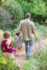 Padre con dos hijos caminando en un jardín - foto de stock