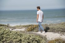 Young man walking on sea coast — Stock Photo